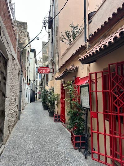 Celosía roja geométrica en la entrada del restaurante, con una planta junto a la puerta