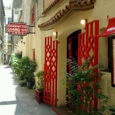 Celosía roja geométrica en la entrada del restaurante, con una planta junto a la puerta