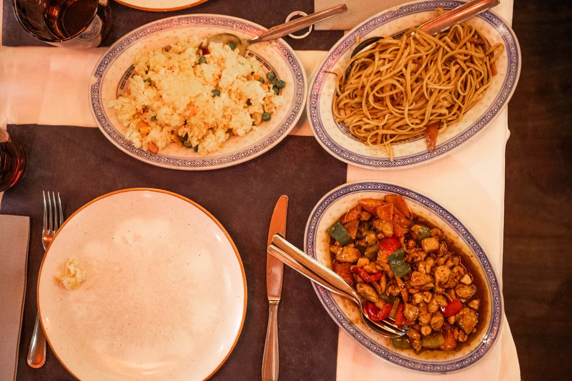 Mesa con arroz frito, tallarines y pollo salteado servidos en fuentes ovaladas